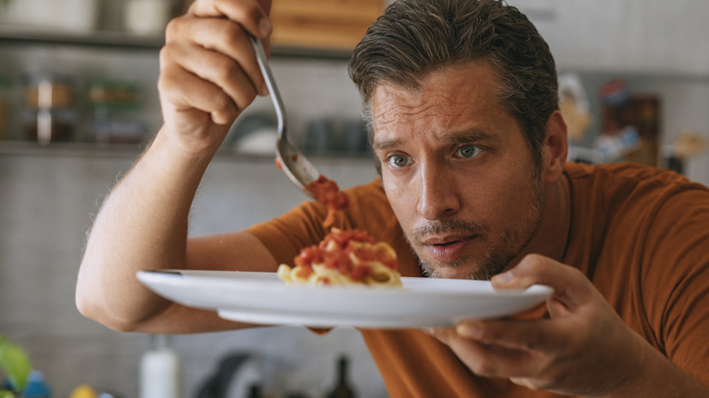 Man pouring sauce on a plateful of spaghetti