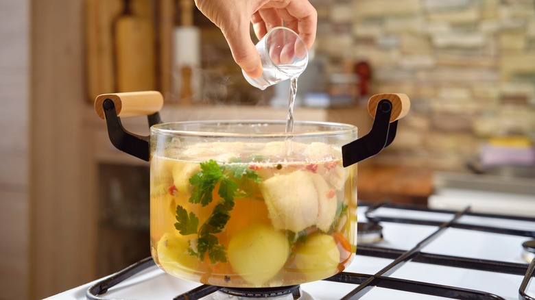 Close-up of vodka poured into a clear pan of fish soup