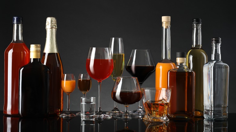 A line-up of generic bottles of alcohol and glasses against a dark background