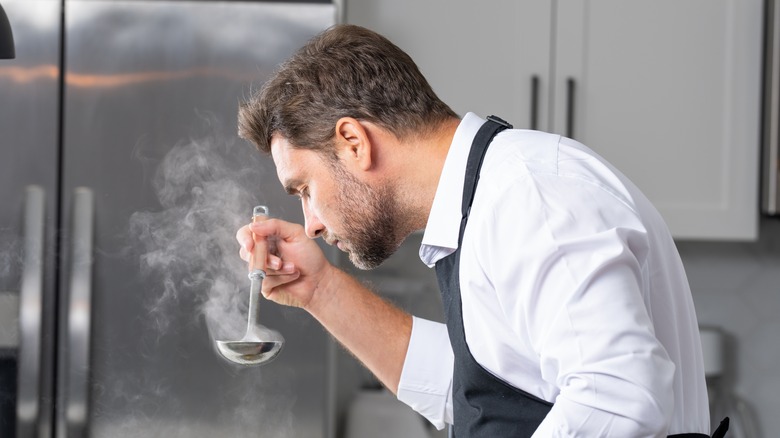 Chef smelling the aroma from a steaming ladle