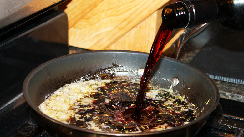 A close-up of red wine being used to make a sauce