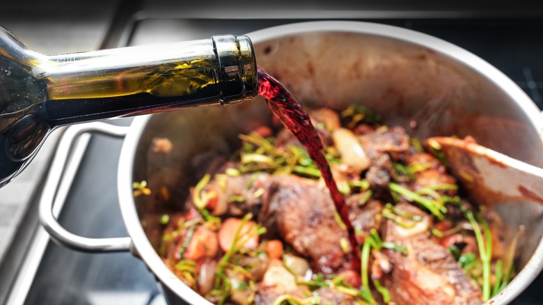 A close-up of red wine being poured into a pan
