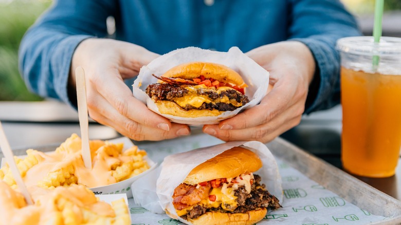 hands display a burger from shake shack
