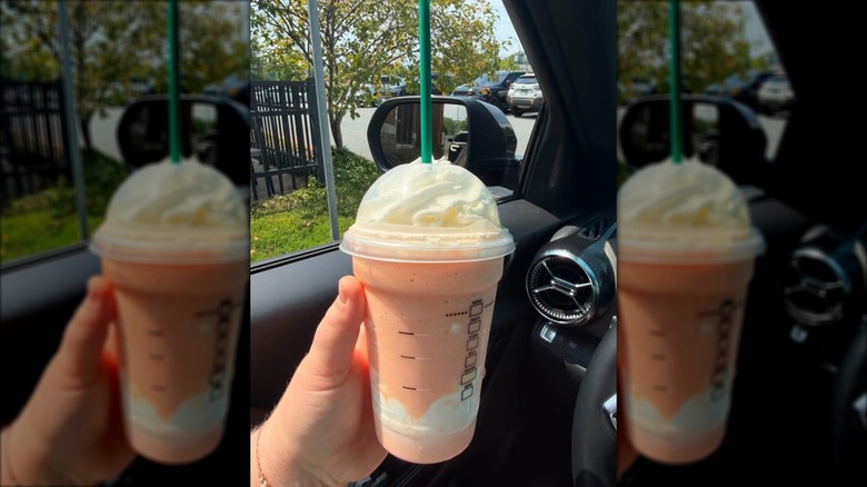 hand holds a starbucks frap in a car