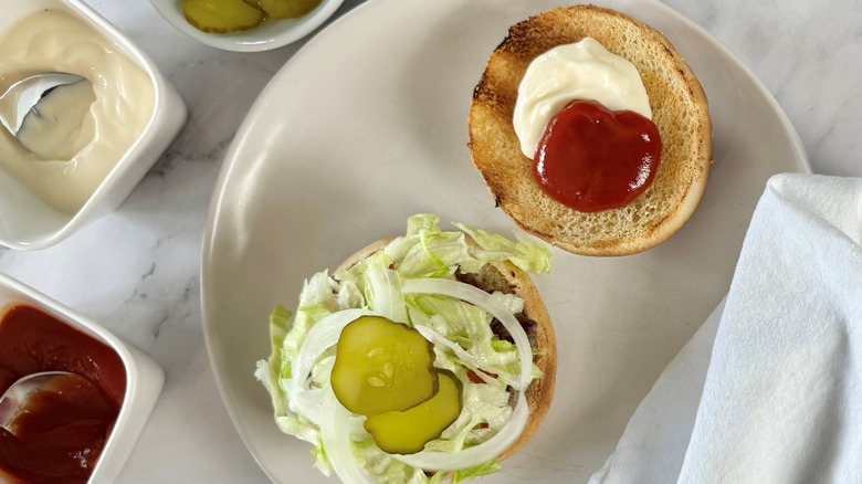 aerial view of an open hamburger showing condiments and toppings on a plate
