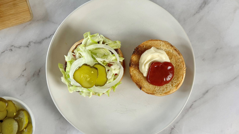 aerial view of open hamburger showing condiments and toppings on white plate