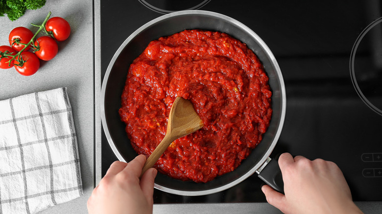 person cooking tomato sauce on stove