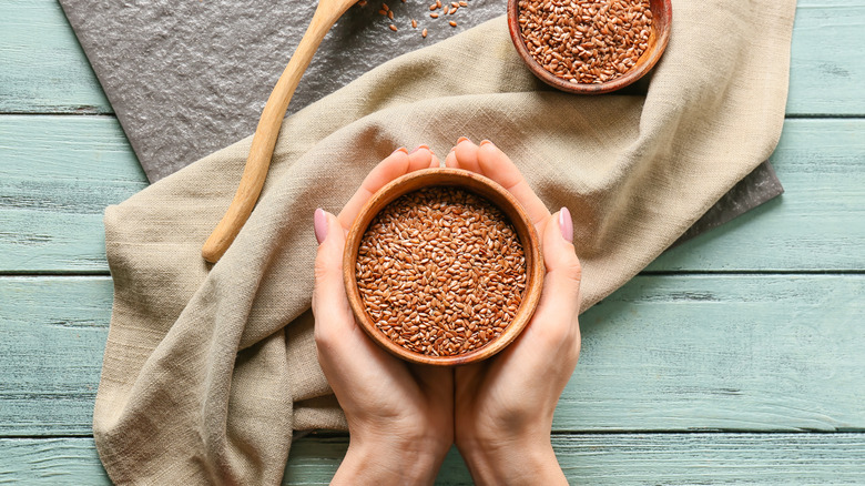 hands holding a bowl of flax seeds
