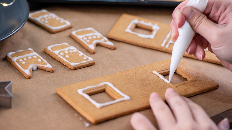 Decorating gingerbread pieces with white icing.