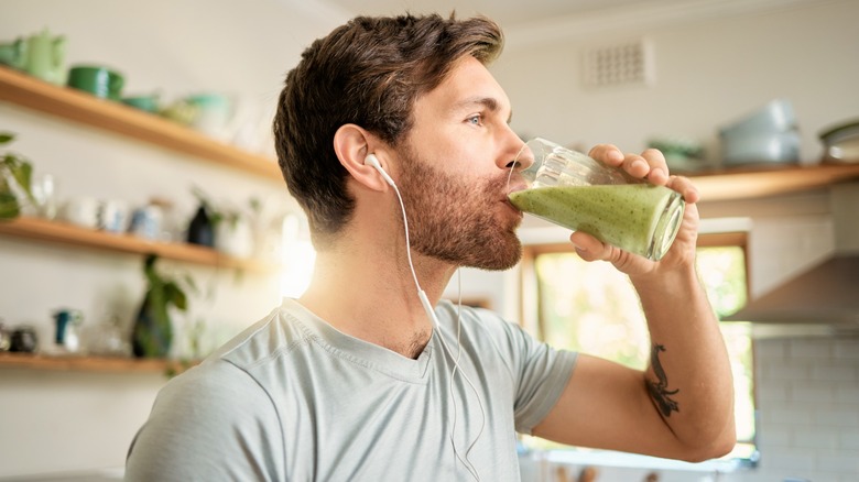 man with headphones drinks a smoothie