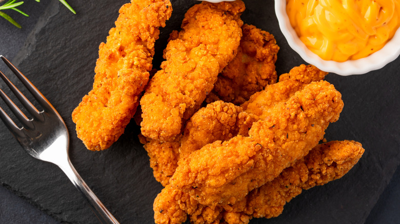 Cooked chicken tenders on a black slate
