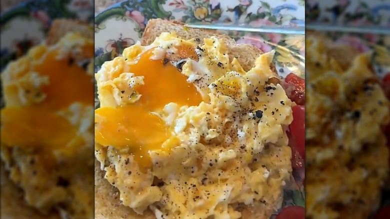 A cut egg yolk on top of a plate of scrambled eggs