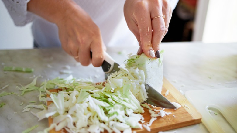 hands chop a head of cabbage into shreds
