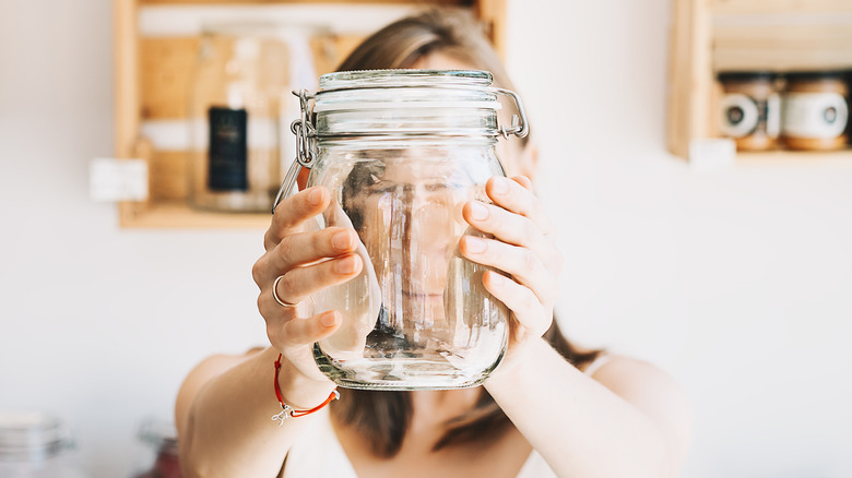 Woman holding out a mason jar in both hands