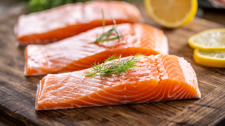 juicy salmon steaks on cutting board with lemons