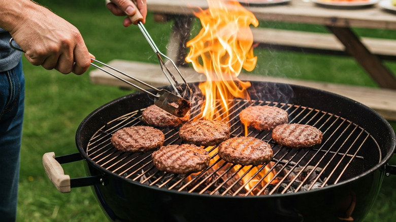 Person BBQing burgers on a grill