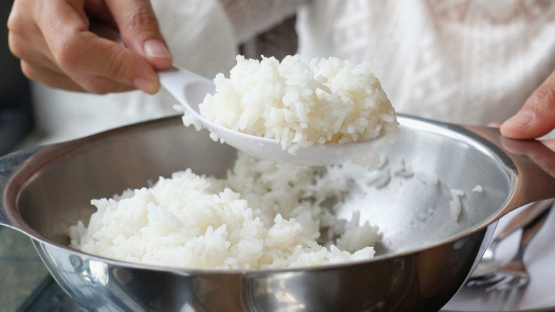 Someone holding a large scoop of cooked rice