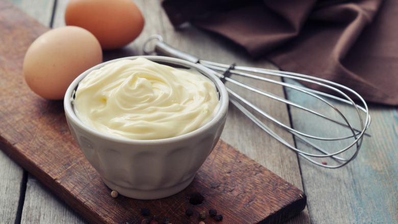 mayo and a whisk sit beside two brown eggs