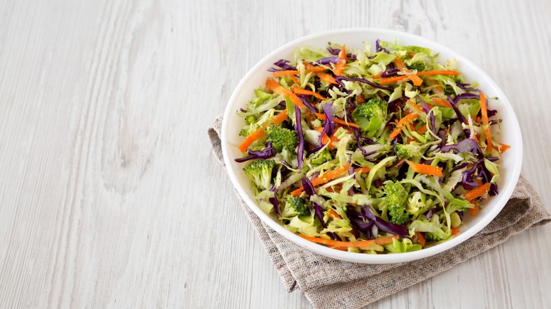 white bowl of broccoli slaw on tea towel
