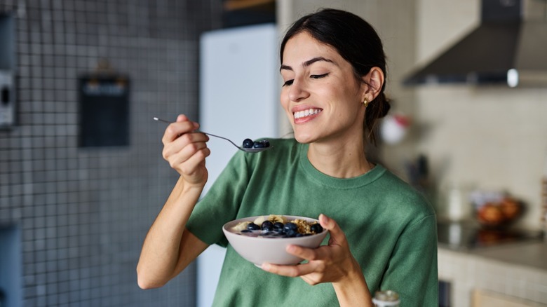 woman eats cereal with fruit and milk