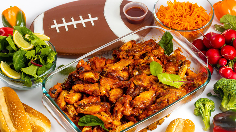 Tray of chicken wings surrounded by ingredients and a football tray.