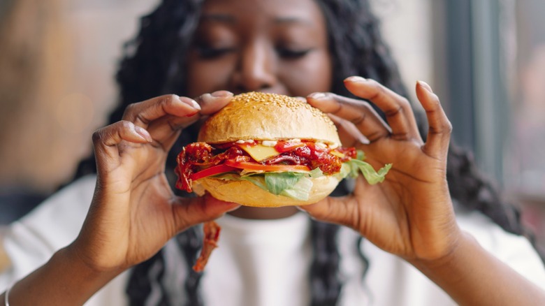 woman holds a burger with toppings