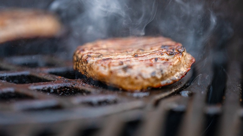burger patty on the smoking grates of a grill