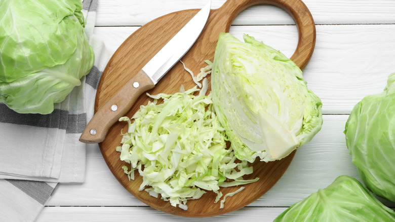 cut cabbage on board with whole heads