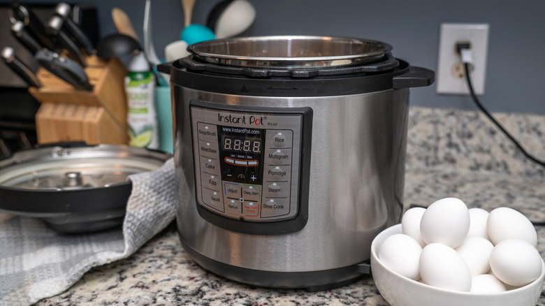 An Instant Pot on kitchen counter beside bowl of white eggs.