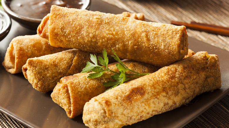 Five browned eggrolls on a gray plate. 