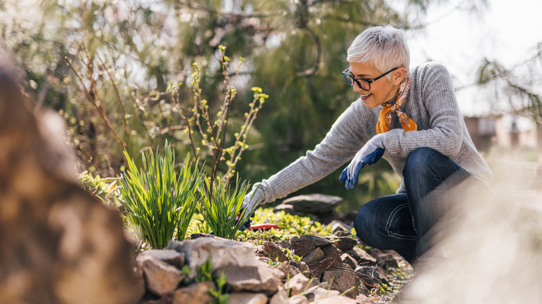 Woman in glasses gardening and smiling.
