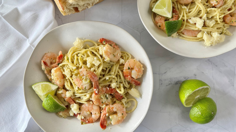 garlic prawn and tomatillo pasta in plate with limes