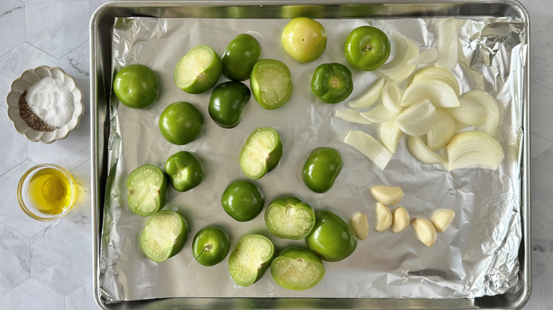 chopped tomatillos, onions, garlic on foil-lined baking sheet