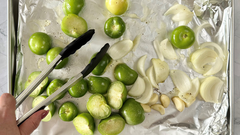 tossing chopped tomatillos, onions, and garlic with oil on foil-lined baking sheet