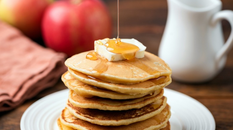 syrup drizzled atop stack of buttered pancakes