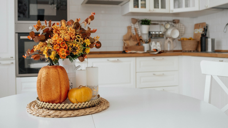 Tabletop in kitchen with small pumpkins and fall leaf decorations.