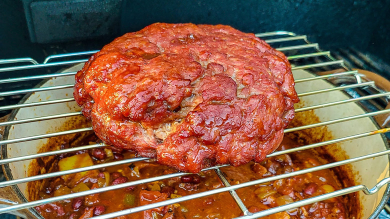 smoked hunk of beef cooks over pot of chili
