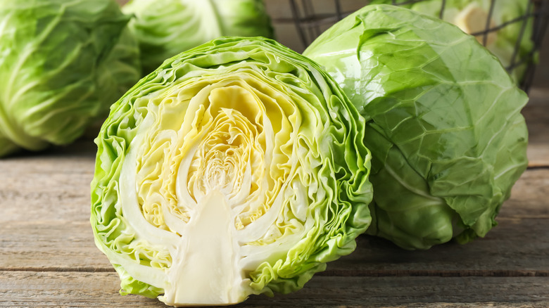 A half and a whole cabbage on a wooden table