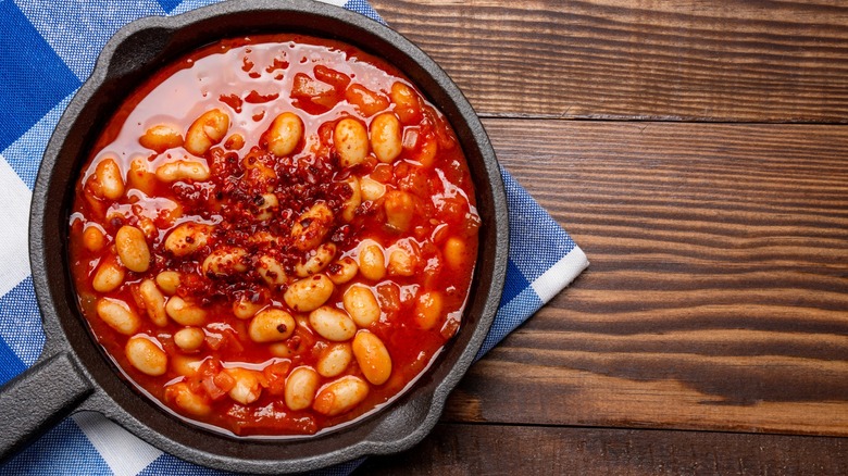 skillet of baked beans with gingham dishcloth