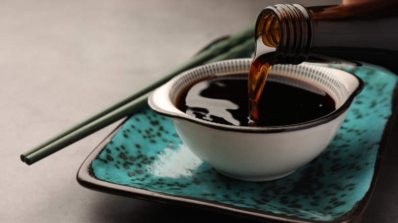 pouring soy sauce into bowl near chopsticks