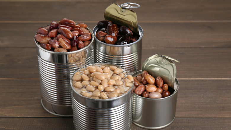 Tin cans of different beans on a wooden table