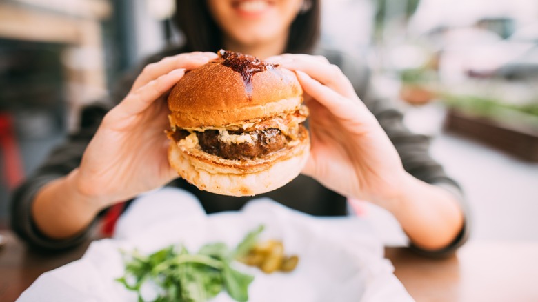 consumer prepares to eat juicy burger