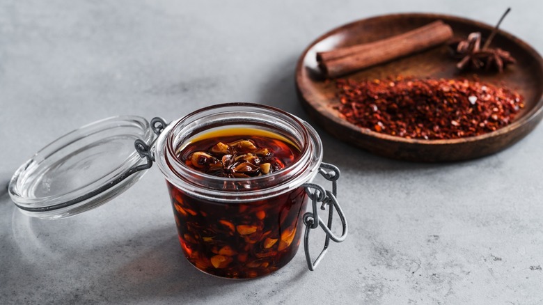 jar of chili crisp alongside dried crushed peppers