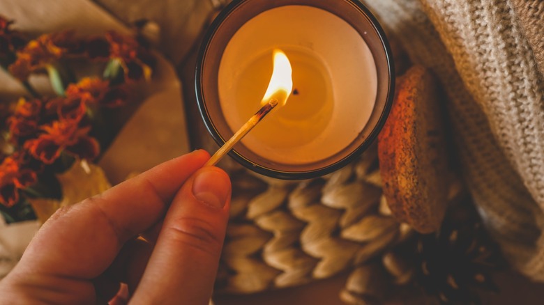 hand lights a candle with a match