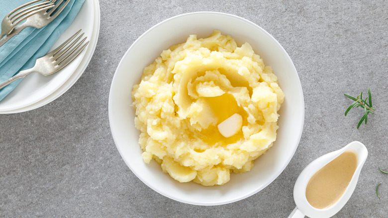 Overhead view of mashed potatoes and gravy in white dishes.