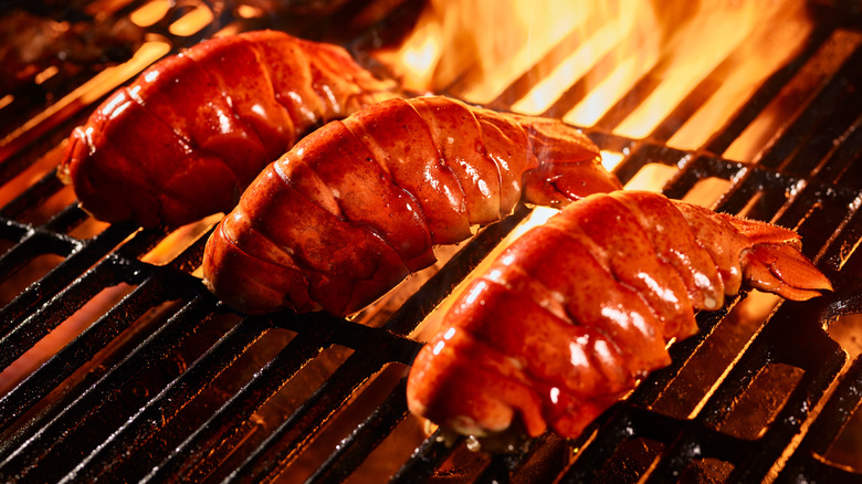 lobster tails on a grill with flames in the background