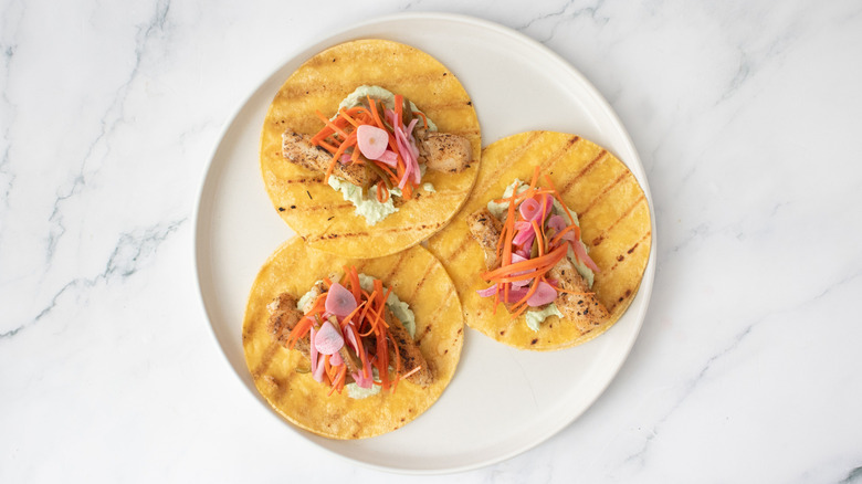 Grilled fish tacos topped with escabeche