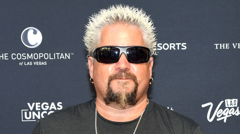 Guy Fieri wearing sunglasses and a black t-shirt