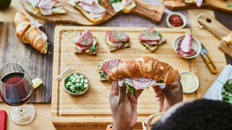 assembling croissant sandwich at table