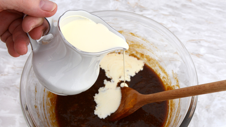 Heavy cream poured from jug into mixing bowl.